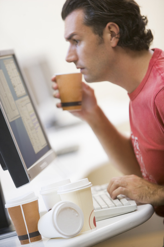 Man in computer room with many empty cups of coffee